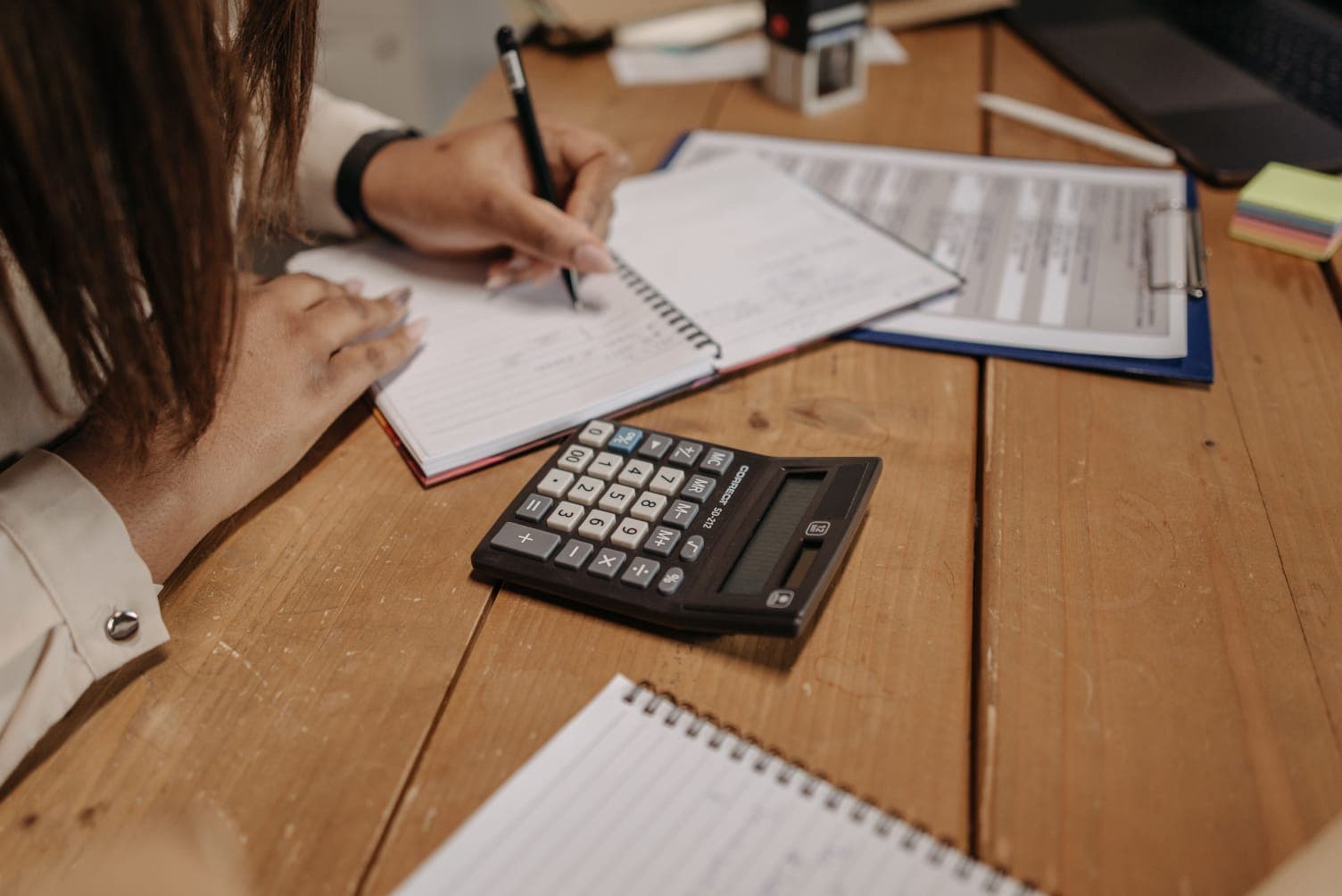 Contadora usando calculadora sobre relatório de índices contábeis