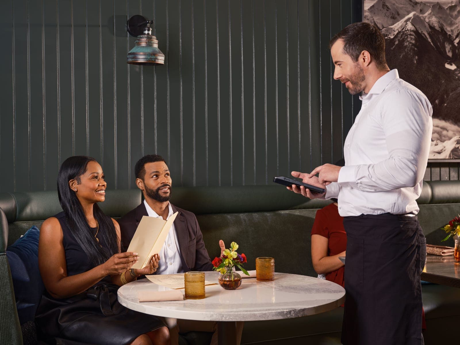 Garçom anotando o pedido dos clientes na mesa pelo celular